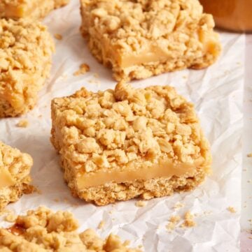 Cut squares of Caramel Oatmeal Bars, on a piece of baking paper.
