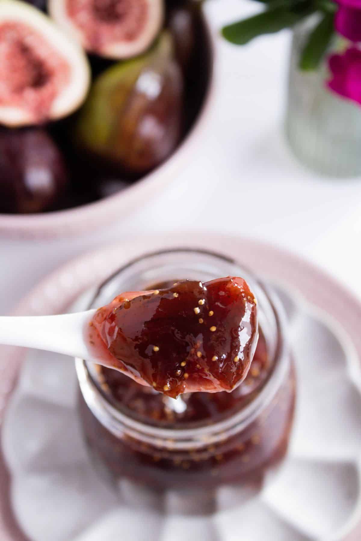 White spoon holding up a scoop of Fig Jam above the open jar.