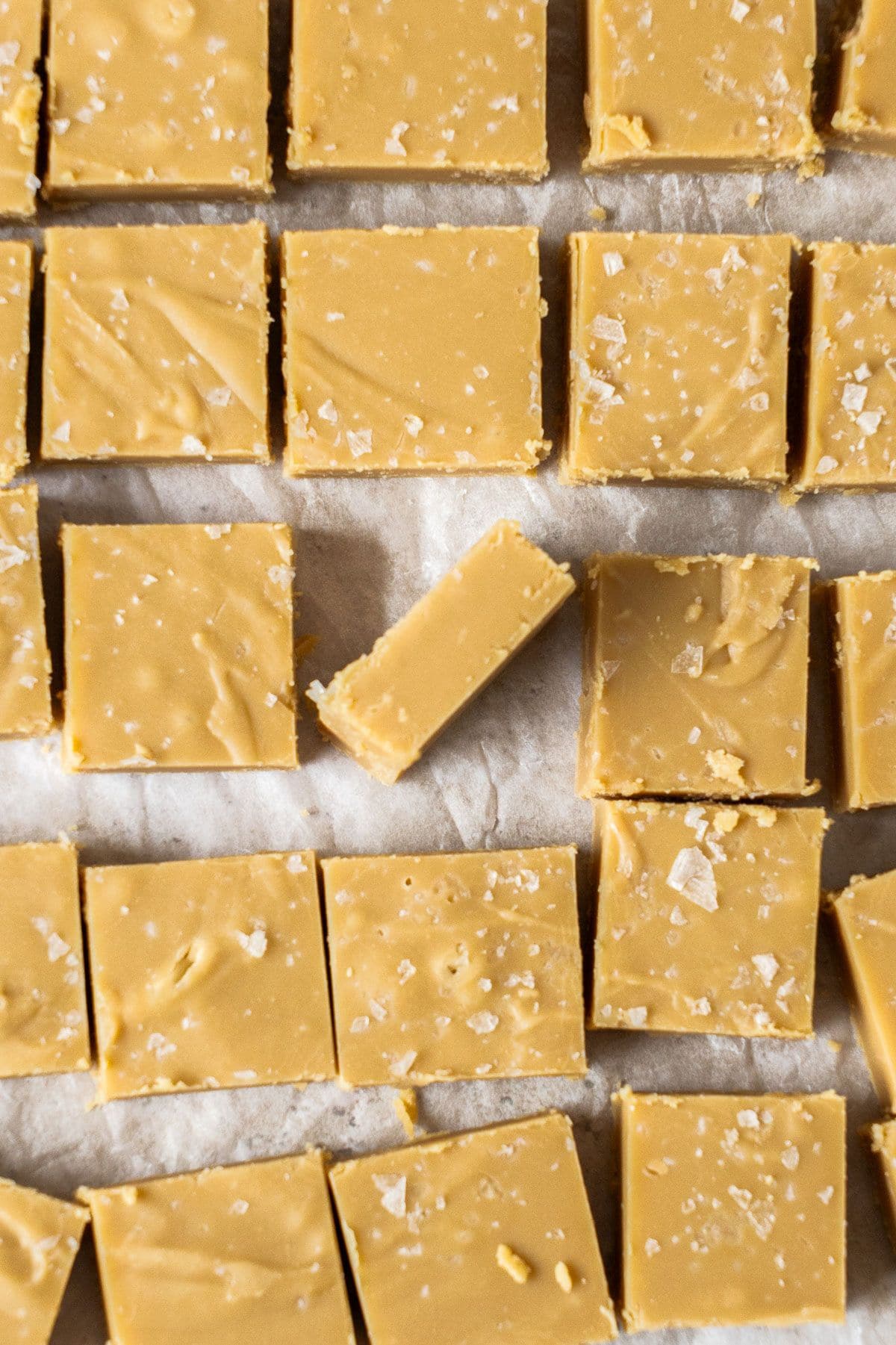 Overhead shot of cut pieces of Caramel Fudge on baking paper, with one piece turned on its side.