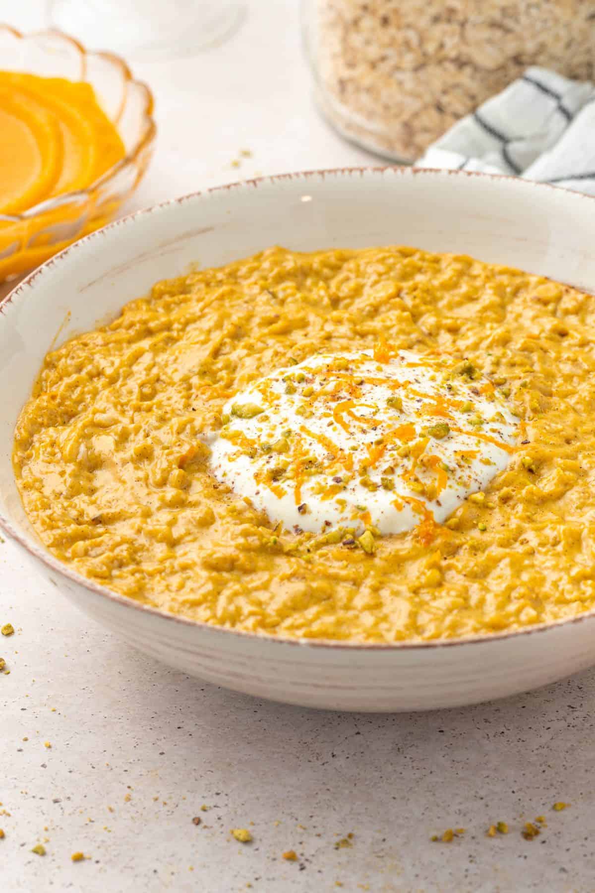 Bowl of pumpkin porridge topped with some yoghurt and orange zest.