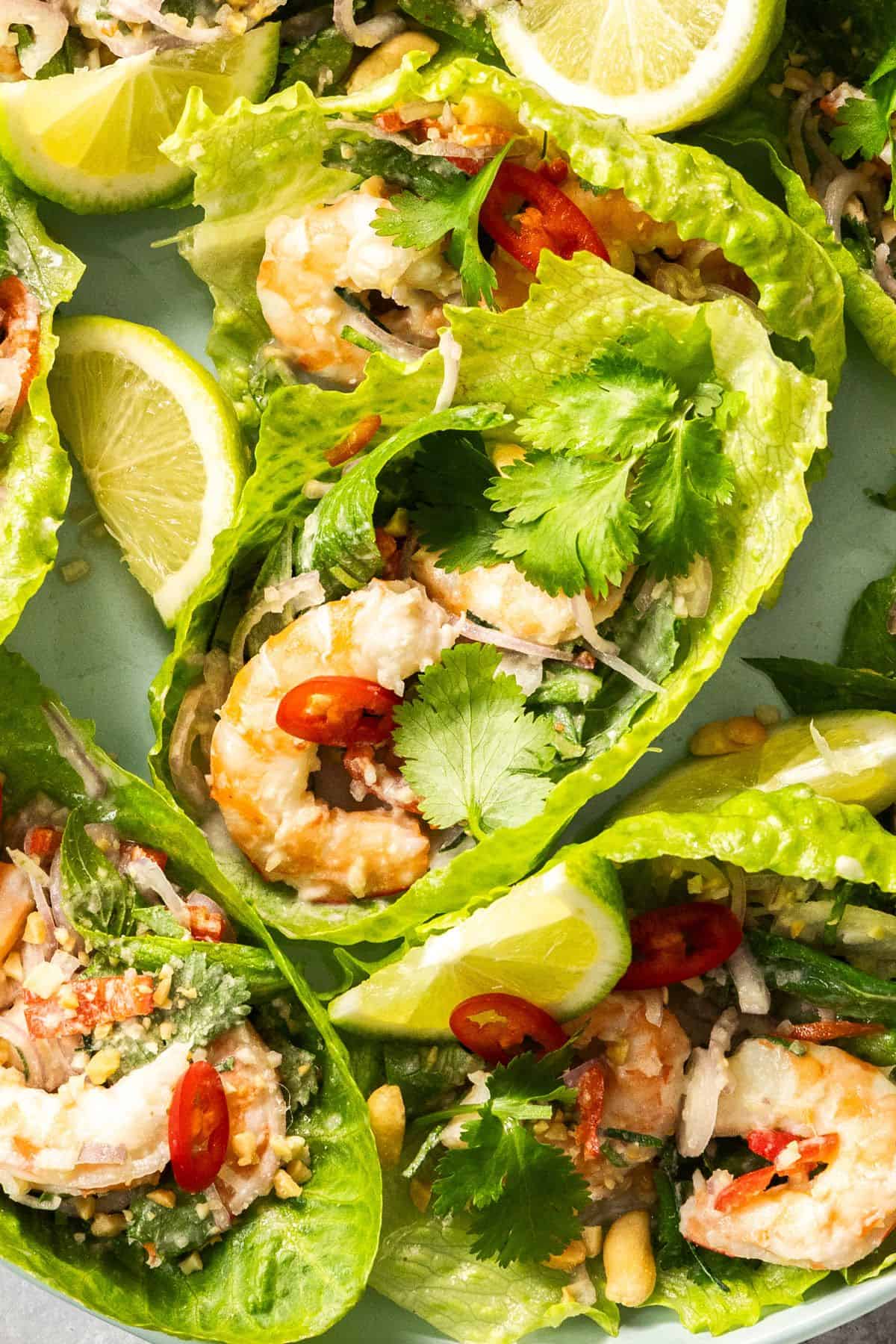 Up close shot of Thai Prawn Salad on a round green plate, showing the detail of a lettuce cup with the salad.
