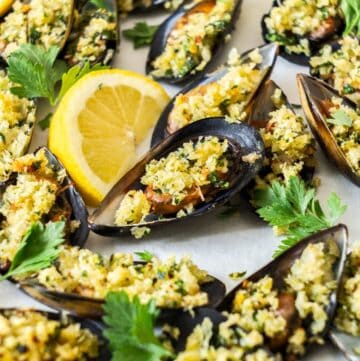 Tray of stuffed Baked Mussels, garnished with some lemon and parsley leaves.
