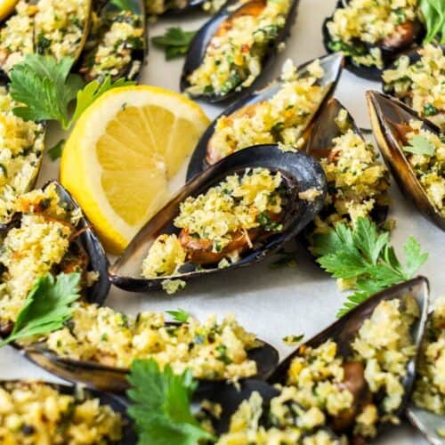 Tray of stuffed Baked Mussels, garnished with some lemon and parsley leaves.