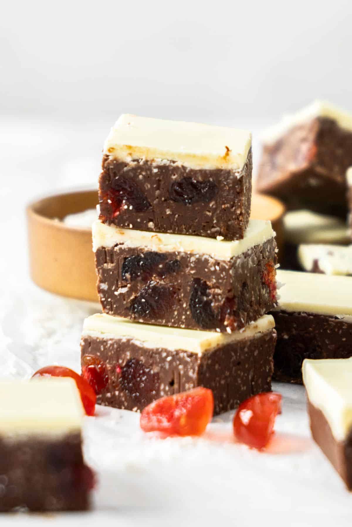 Stack of three pieces of Dark Chocolate Cherry Fudge, with some other pieces in the background.