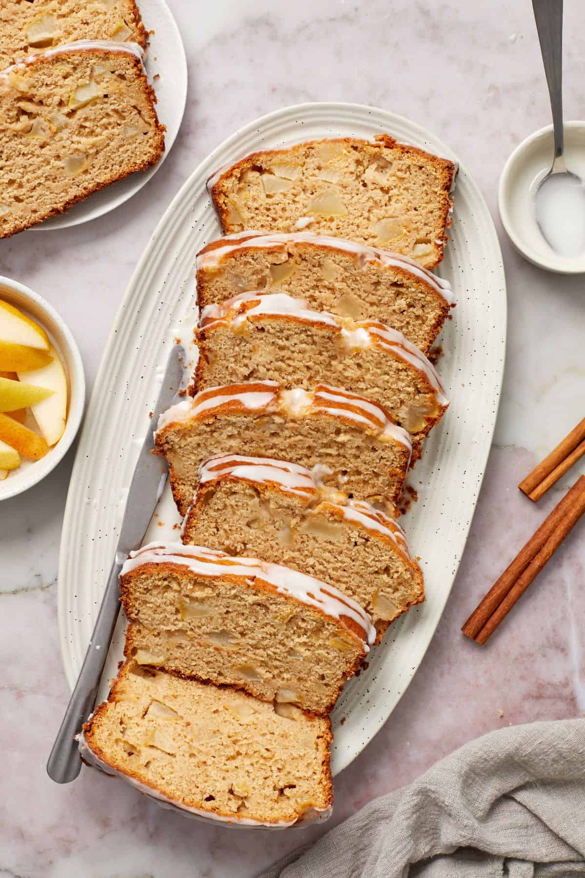 Slices of Pear Loaf Cake on a white oval platter.