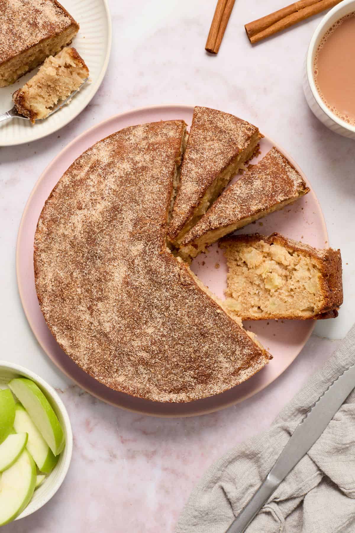 Apple Tea Cake, with three slices cut, and one slice on the side to show the texture of the cake.