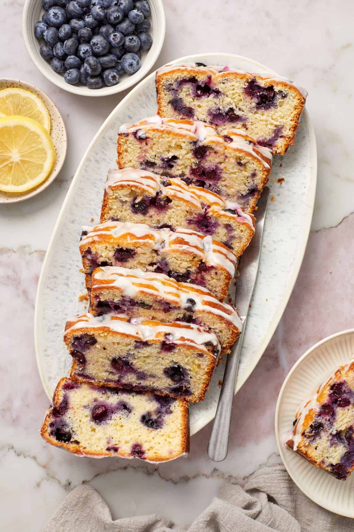 Slices of Blueberry Loaf Cake on a white oval platter.