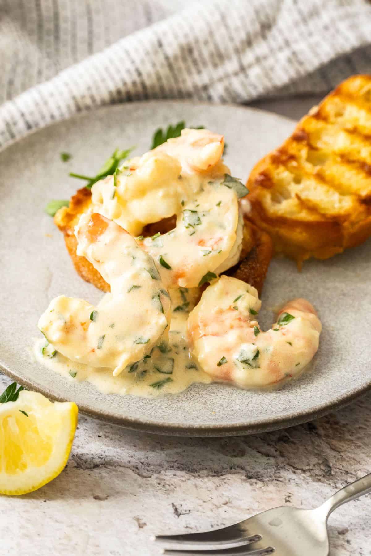 Serving of Creamy Lemon Garlic Prawns on a round grey plate with two pieces of grilled bread.