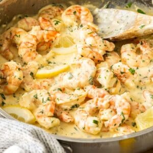 Frying pan with Creamy Lemon Prawns, and a wooden spoon resting in the pan.