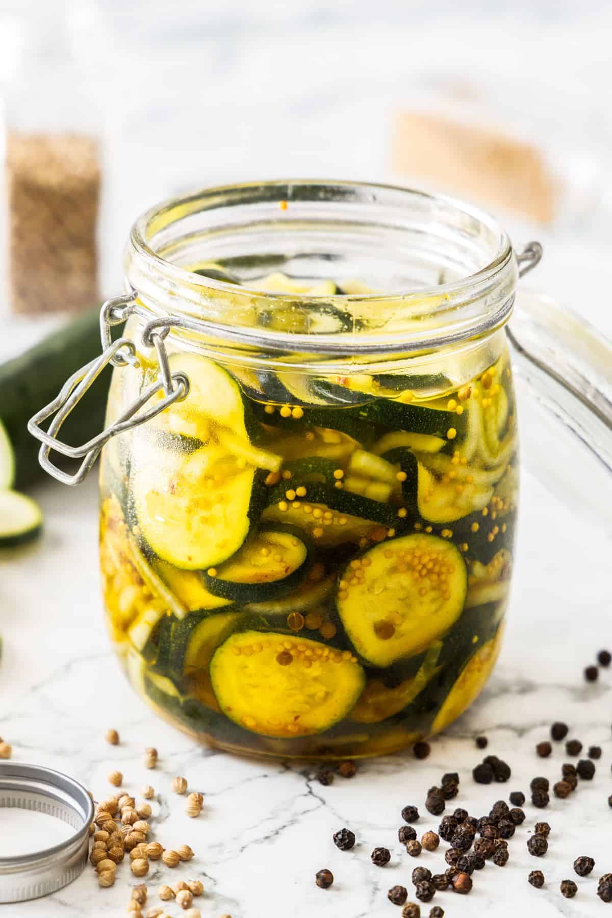 Jar of Pickled Zucchini, with some of the spices and seasonings used around the edge.