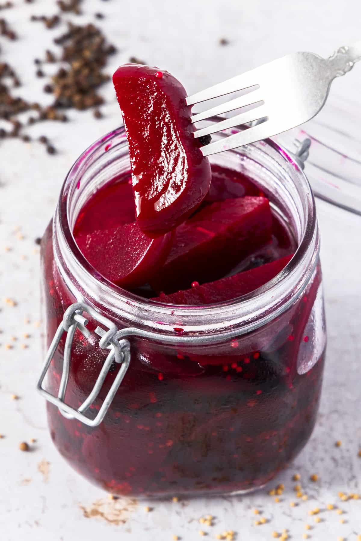 Glass jar of Pickled Beetroot, with a fork lifting a piece from the jar.