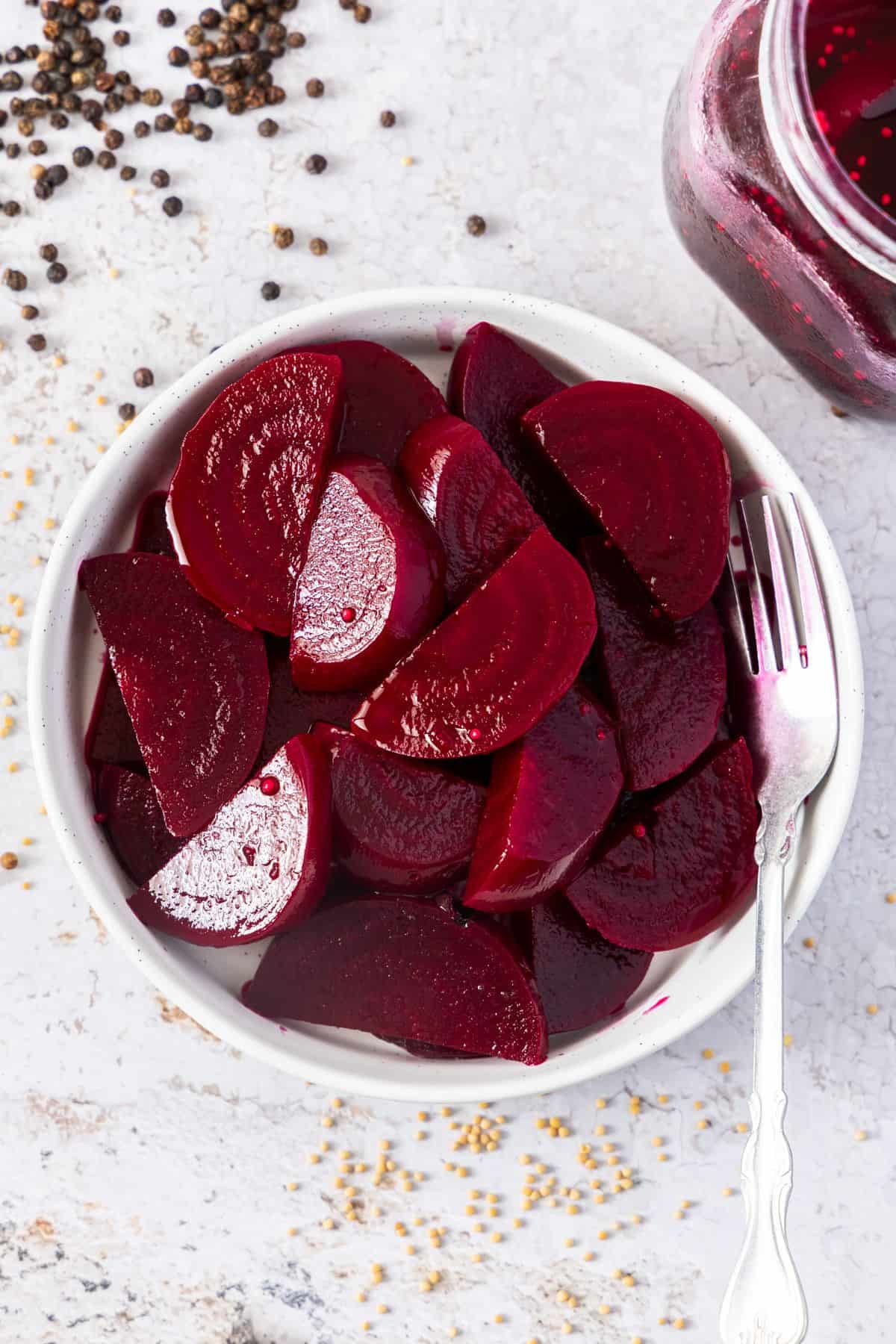 Round white dish with Pickled Beetroot, and a fork resting on the edge of the dish.