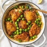 Round dish with the Braised Chicken,, Lemon and Olives, with a spoon resting in the dish.