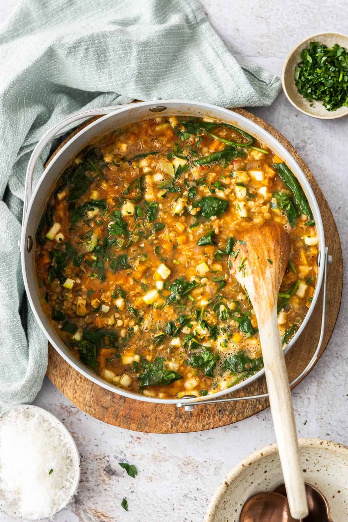 Large saucepan with the cooked Red Lentil Soup, with a wooden spoon resting in the pot.