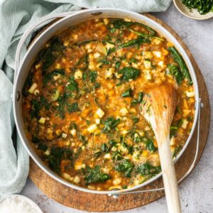 Large saucepan with the cooked Red Lentil Soup, with a wooden spoon resting in the pot.