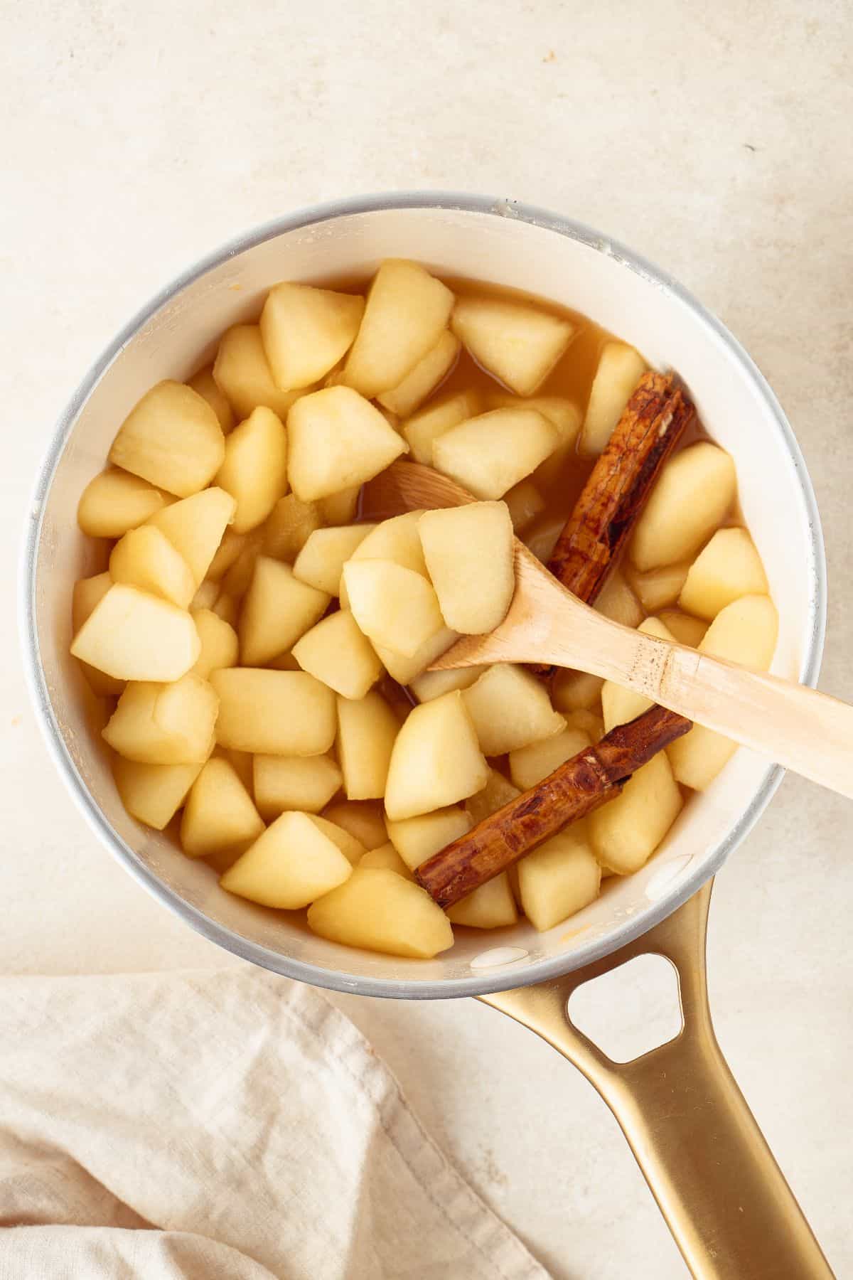 Stewed Apples in a saucepan, with a wooden spoon sitting in the pan.