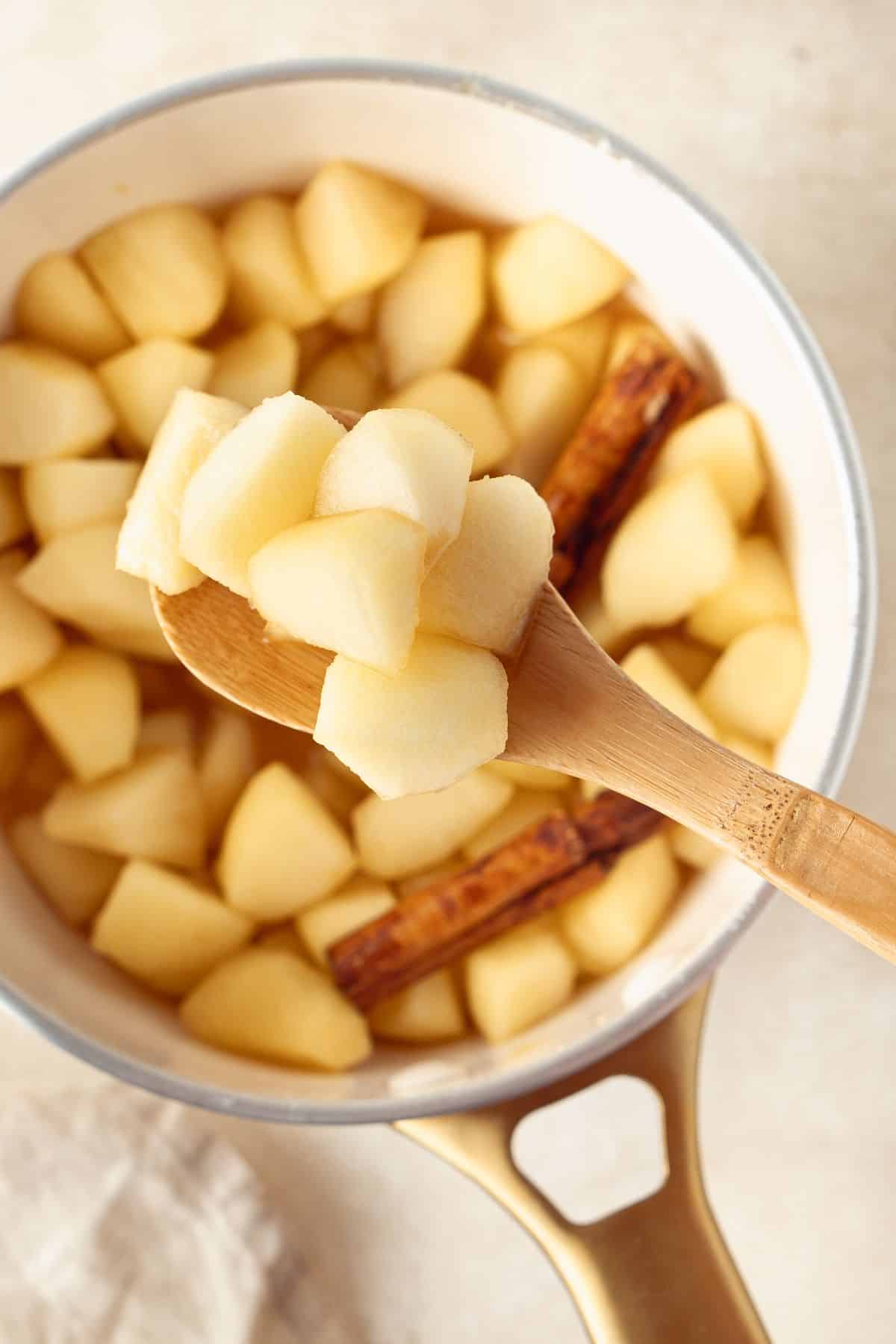 Saucepan of Stewed Apples, with a wooden spoon lifting some up out of the pan.