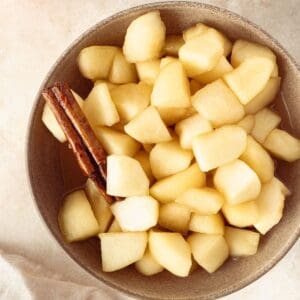 Small round dish of Stewed Apples, with a cinnamon stick sitting in the bowl.