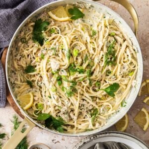 Large frying pan filled with Creamy Tuna Pasta, topped with fresh dill, parsley and some slices of lemon.