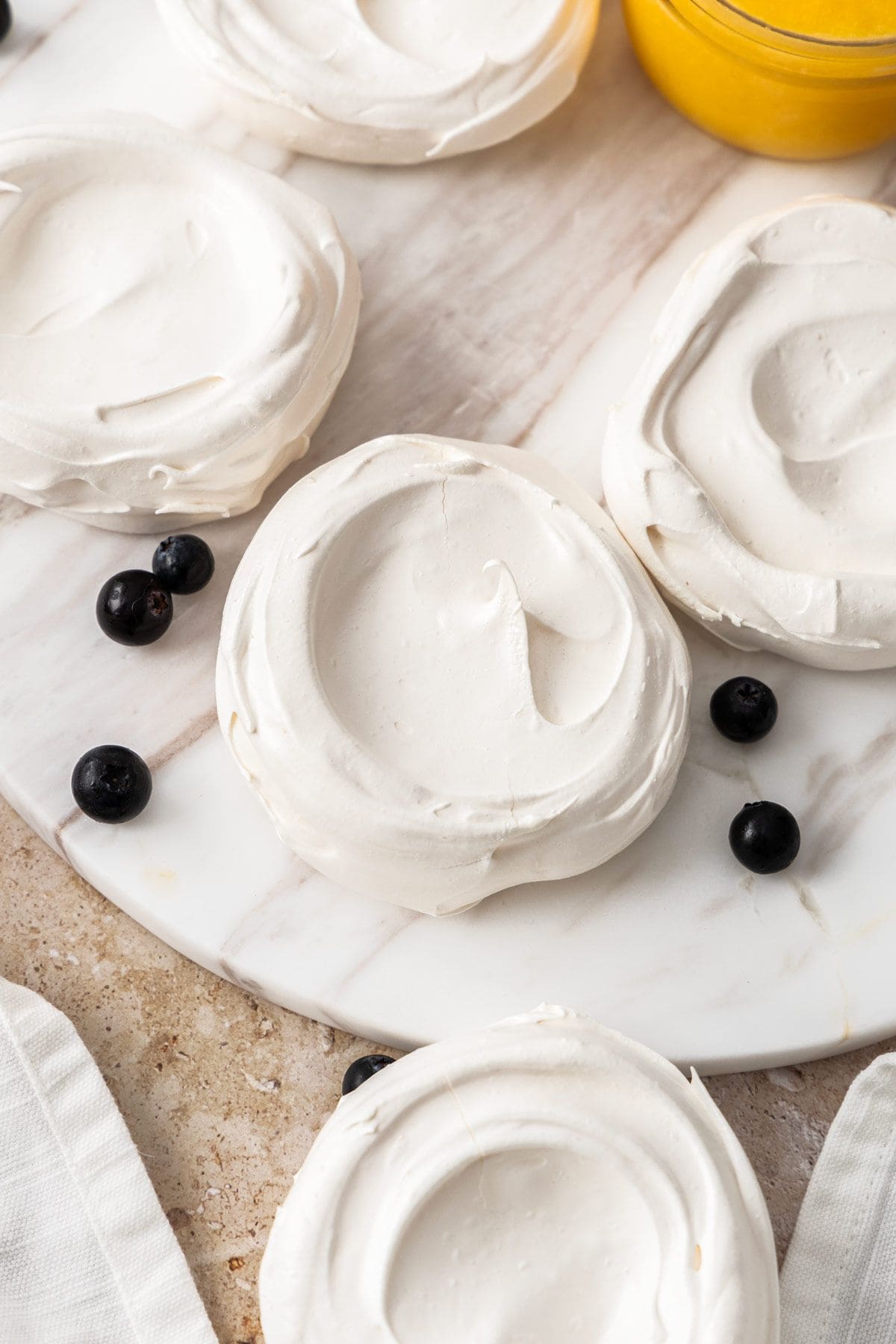 Meringue nests on a round white marble plate.