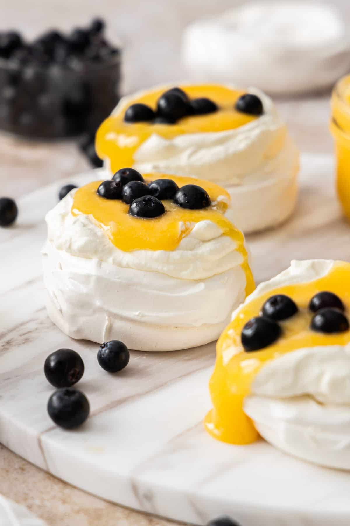 Meringue nests topped with whipped cream, lemon curd and blueberries.