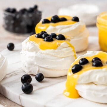 Meringue nests topped with whipped cream, lemon curd and blueberries.