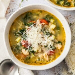 Large saucepan with the cooked Mediterranean Cannellini Bean Soup, with a wooden spoon resting in the pot.