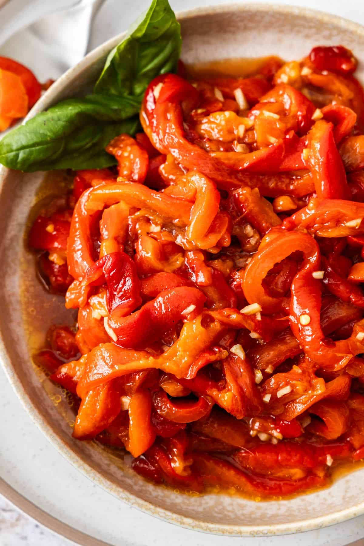 Round plate with Roasted Red Peppers, garnished with a couple of basil leaves.