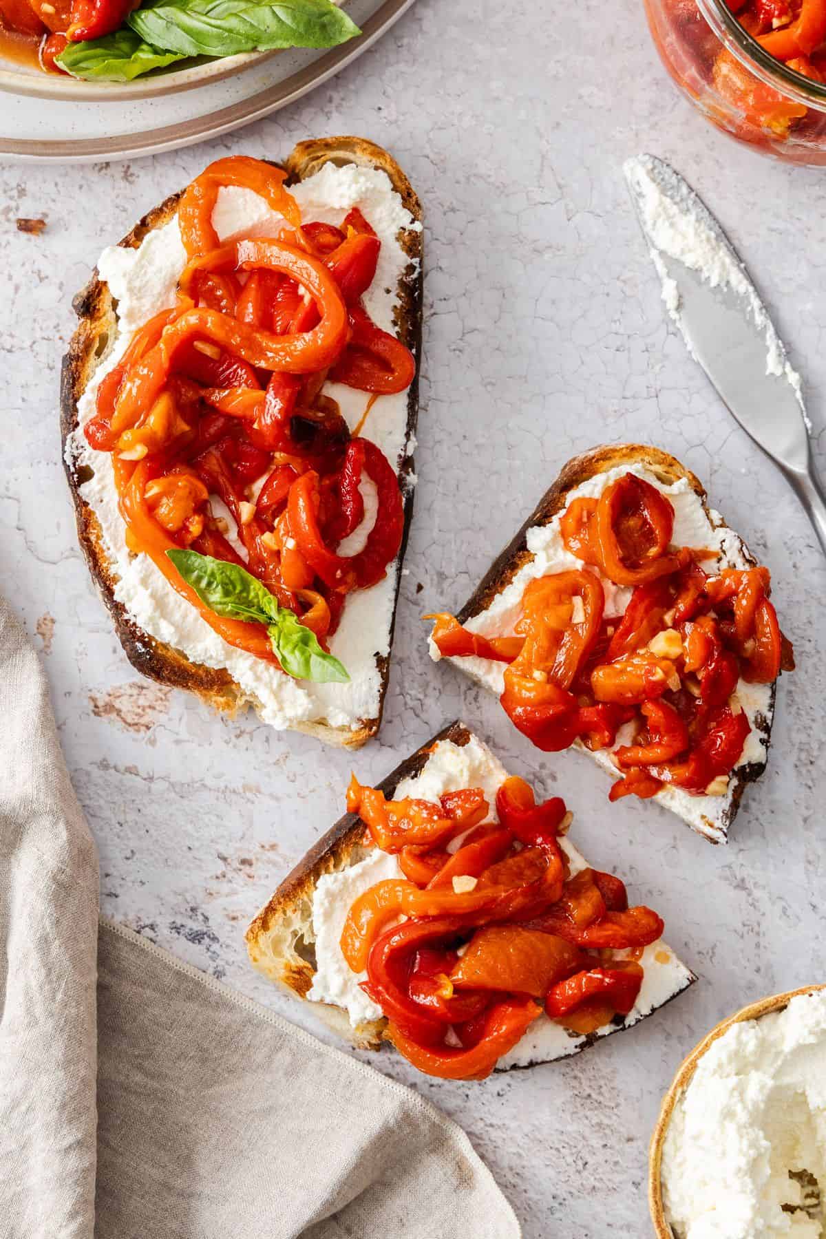 A couple of pieces of toasted bread topped with cream cheese and strips of roasted peppers.