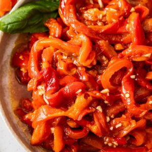 Round plate with Roasted Red Peppers, garnished with a couple of basil leaves.