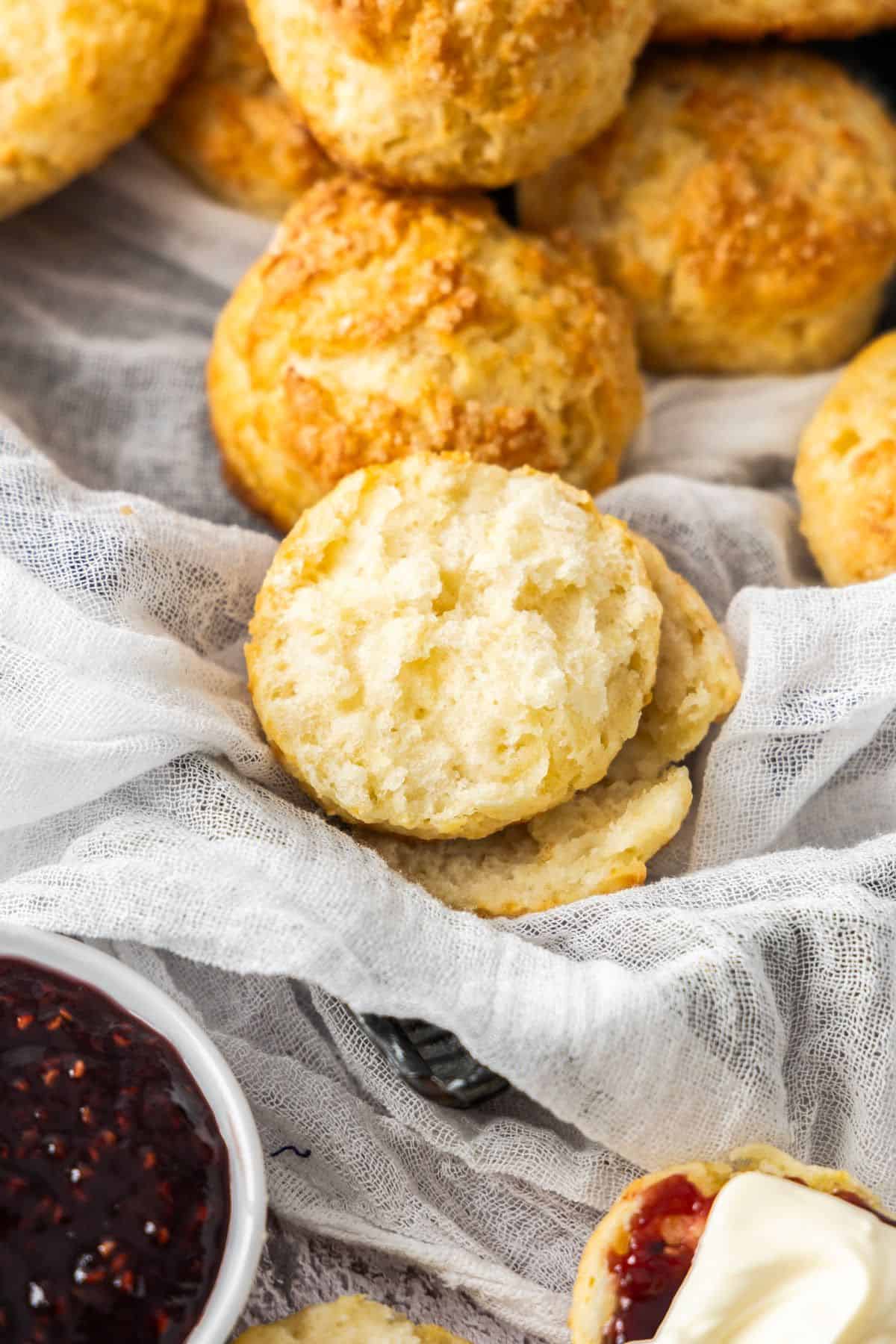 Buttermilk Scones sitting on a white cloth, with one scone broken in half.