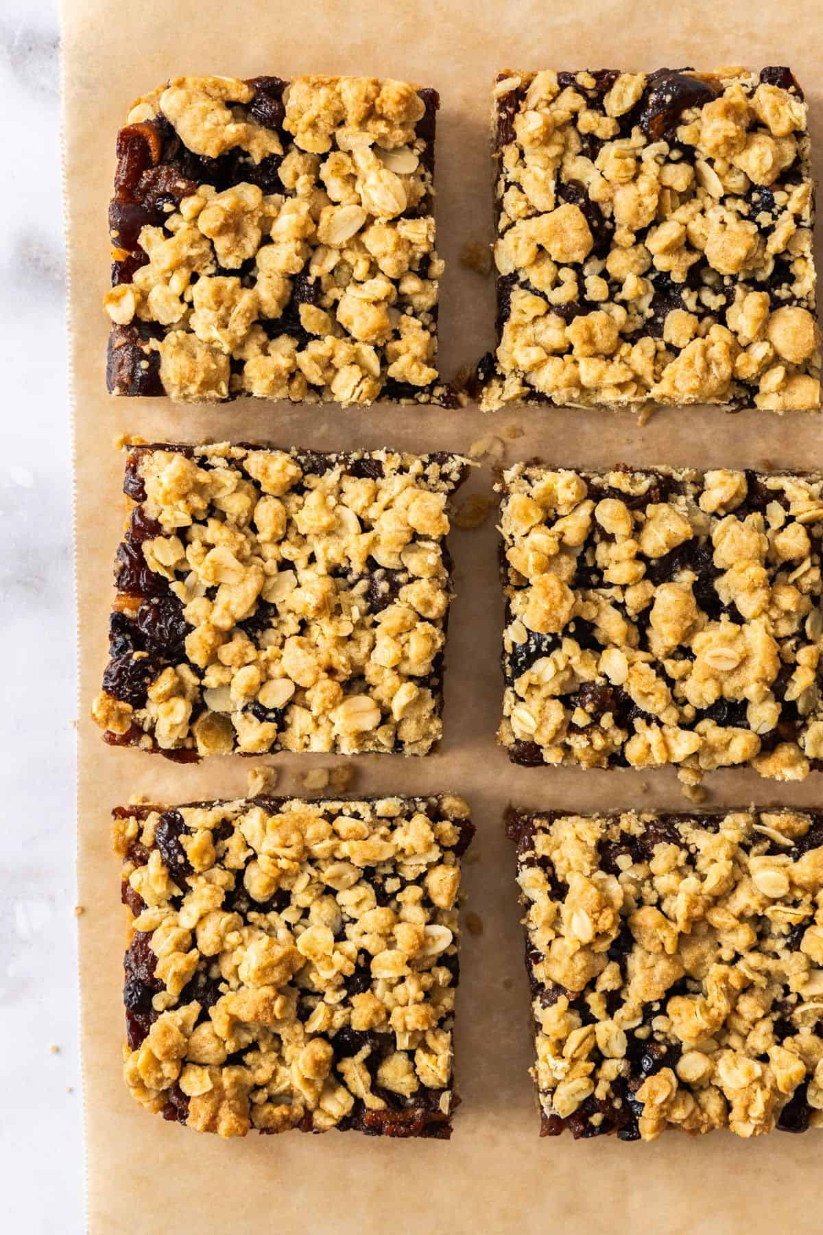 Six cut pieces of Fruit Mince Oatmeal Bars sitting on some brown paper.