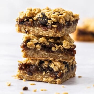 Stack of three pieces of Fruit Mince Oatmeal Bars sitting on a marble benchtop.