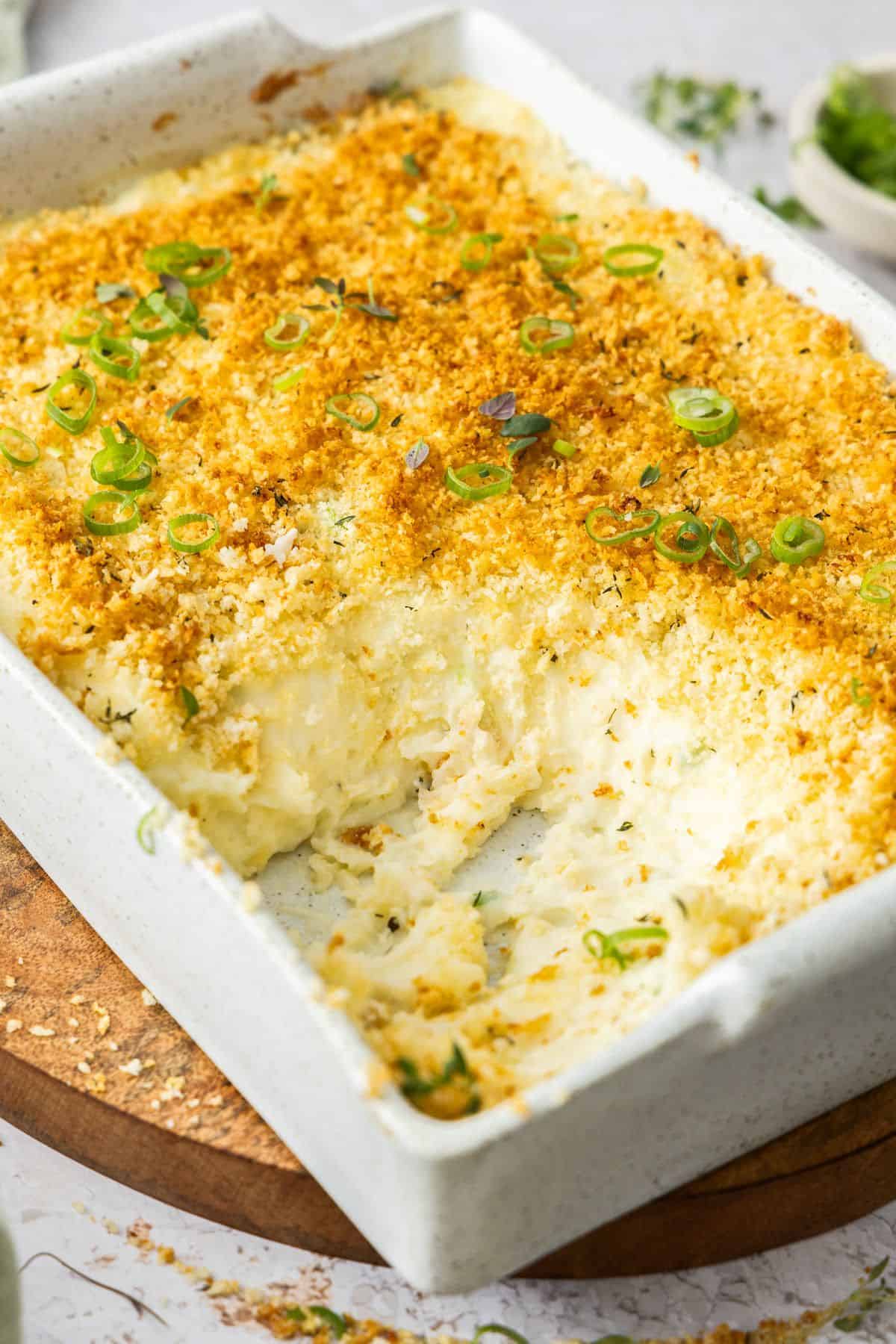 Rectangular dish of Baked Mashed Potatoes with a serve of potato removed to show the inside of the dish.