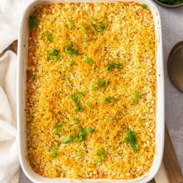 White rectangular baking dish, sitting on a wooden board, containing Baked Mashed Sweet Potato.