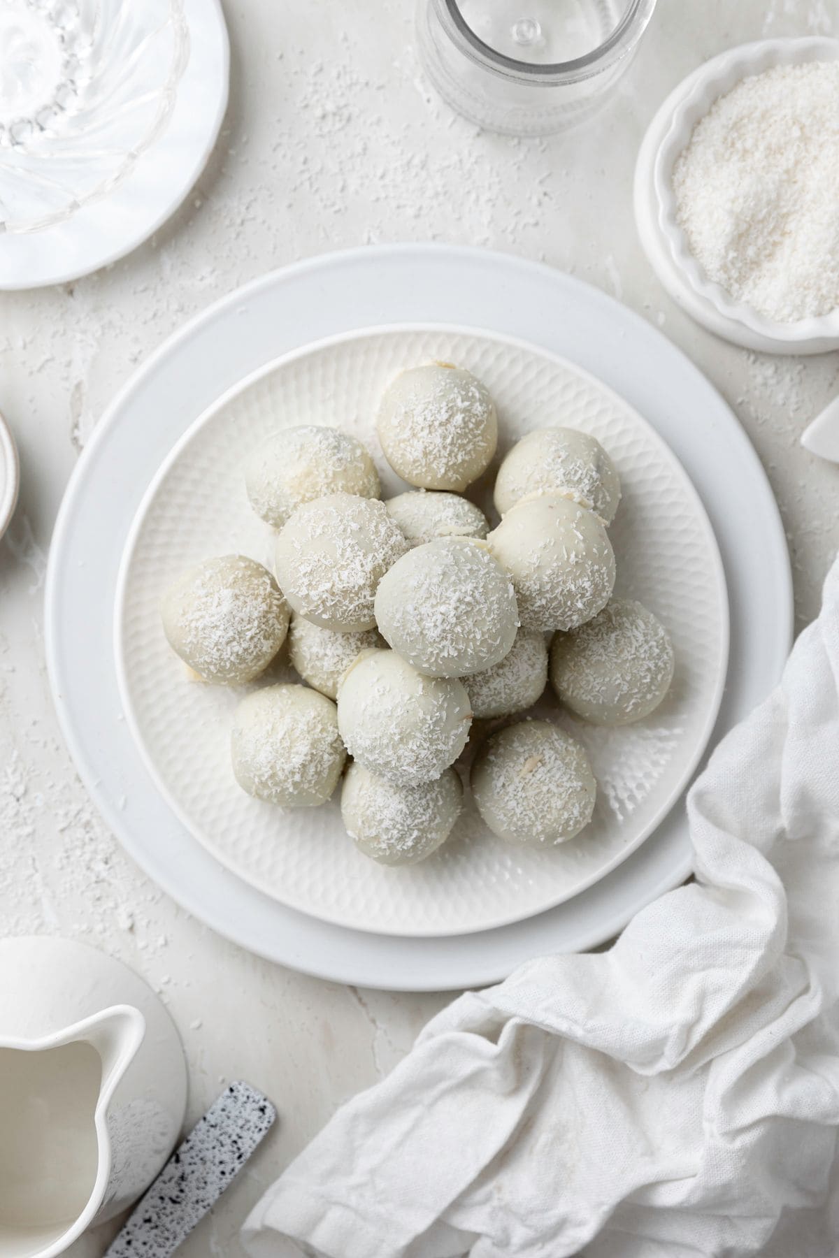 Round white plate with a stack of Coconut Truffles, and white cloth on the edge.