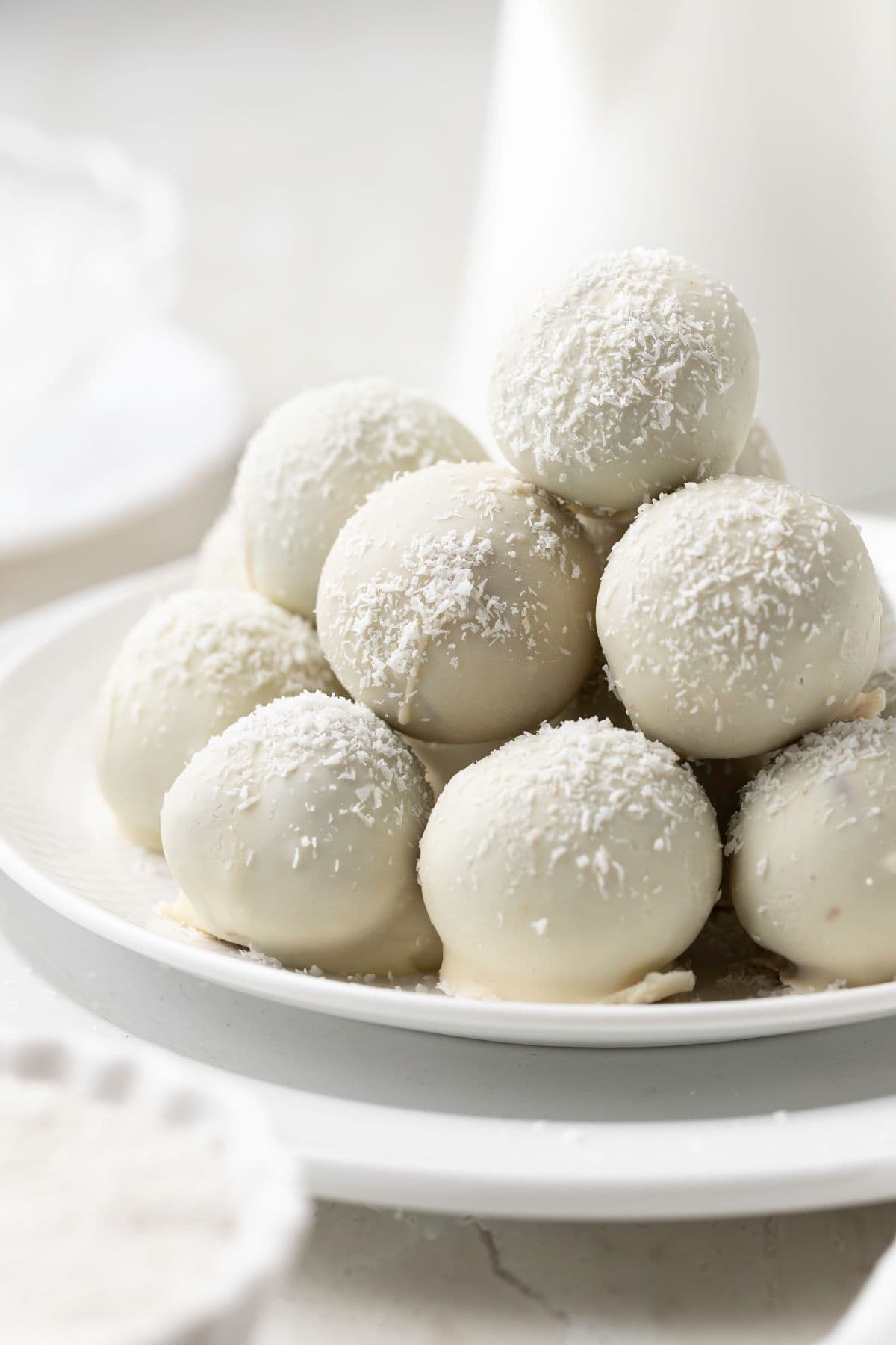 Round white plate with a stack of Coconut Truffles.