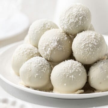 Round white plate with a stack of Coconut Truffles.