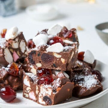 Round white plate with cut pieces of Rocky Road, sitting on a white bench top.