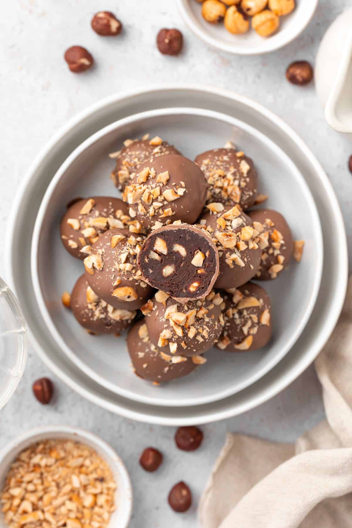 Round dish with stack of Hazelnut Truffles, with one cut in half to show the inside.