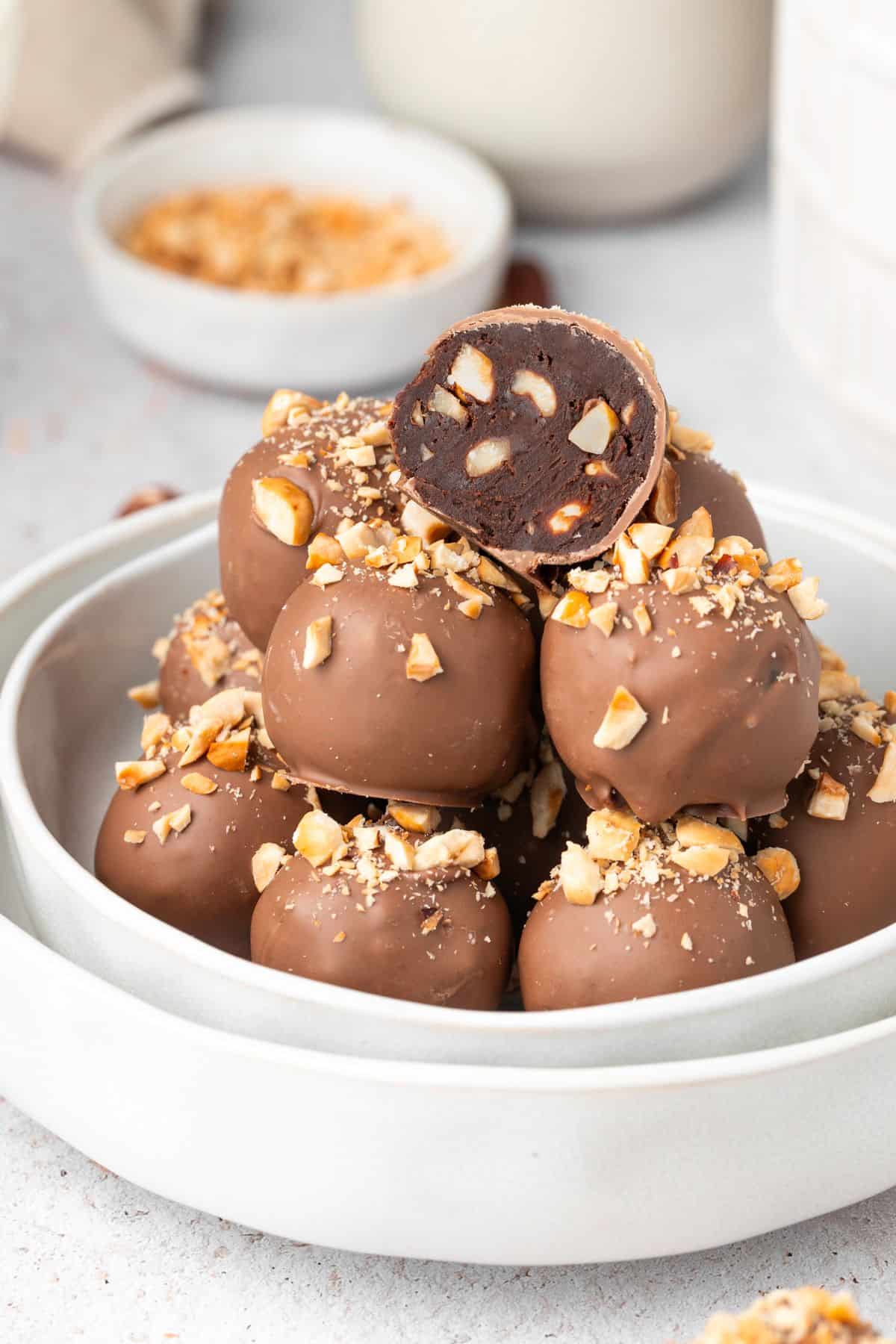 Round dish with stack of Hazelnut Truffles, with one cut in half to show the inside.