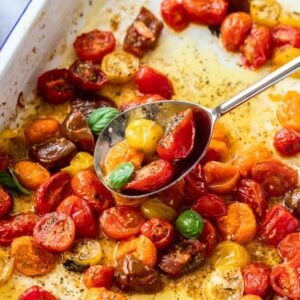 Baking dish with Roasted Cherry Tomatoes, with a silver spoon scooping into them.