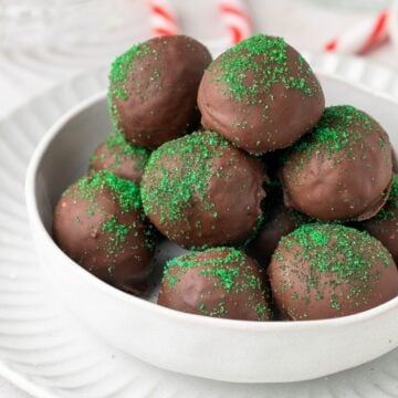 Round white dish of Chocolate Peppermint Truffles, sitting on a round white plate.