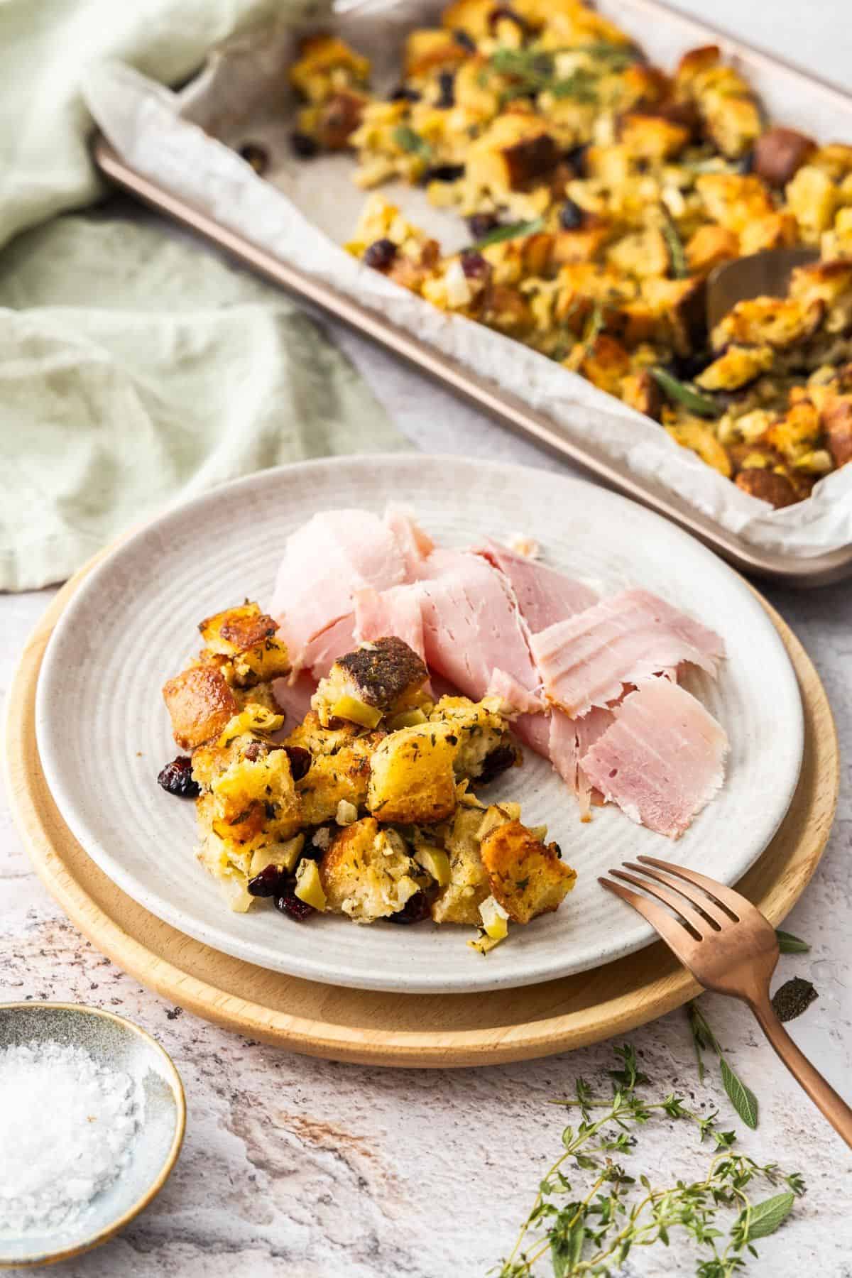 Serving on Crispy Stuffing on a round white plate, along with some baked ham.