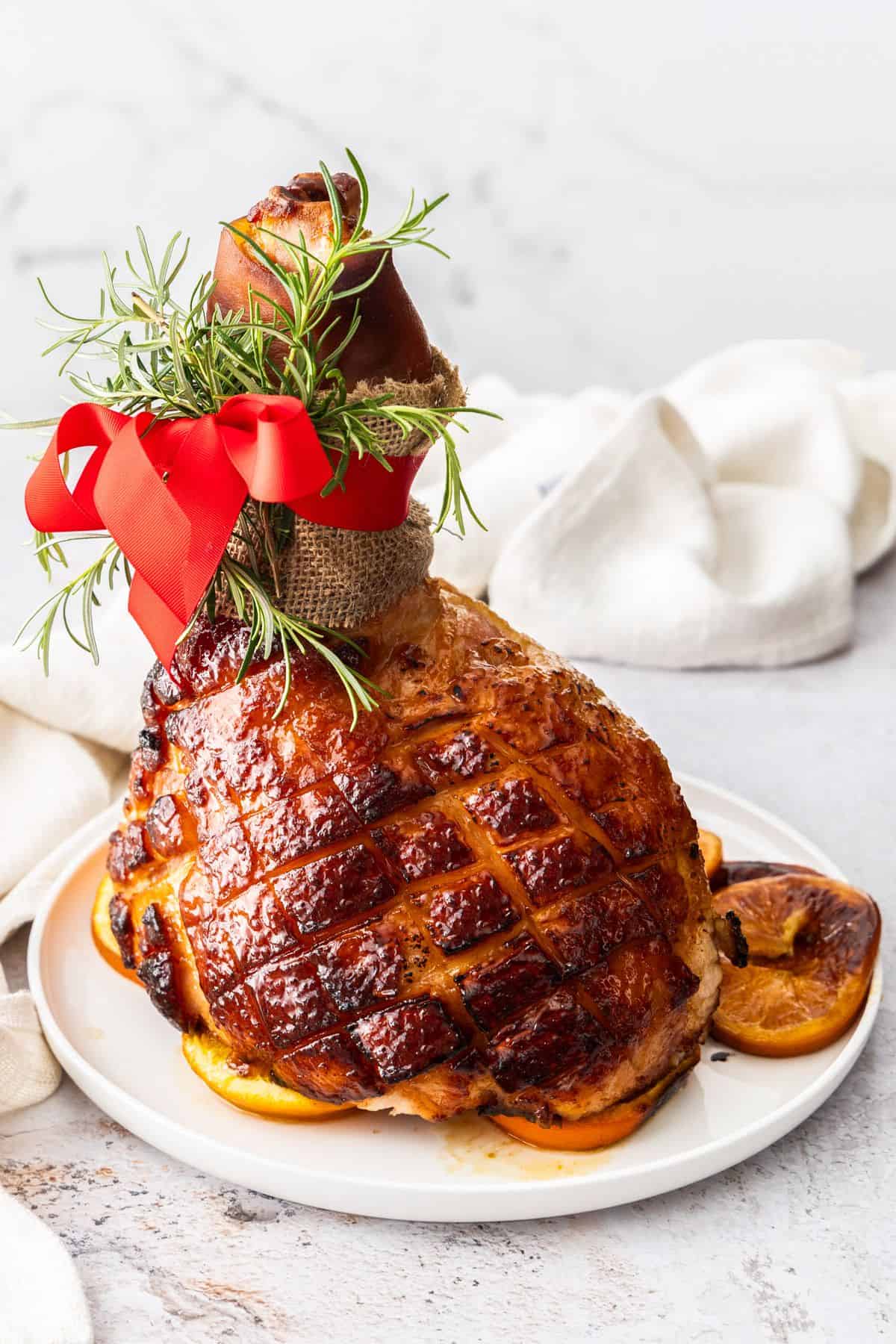 Maple Glazed Ham, sitting on some orange slices on a round white plate.