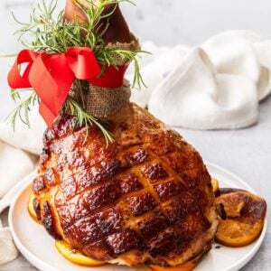 Maple Glazed Ham, sitting on some orange slices on a round white plate.