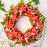 Watermelon and Feta Wreath Salad, arranged on a round white platter, sitting on a grey cloth.