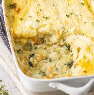 Rectangular dish off Chicken Cottage Pie, sitting on a wooden board, with a serve having been removed.