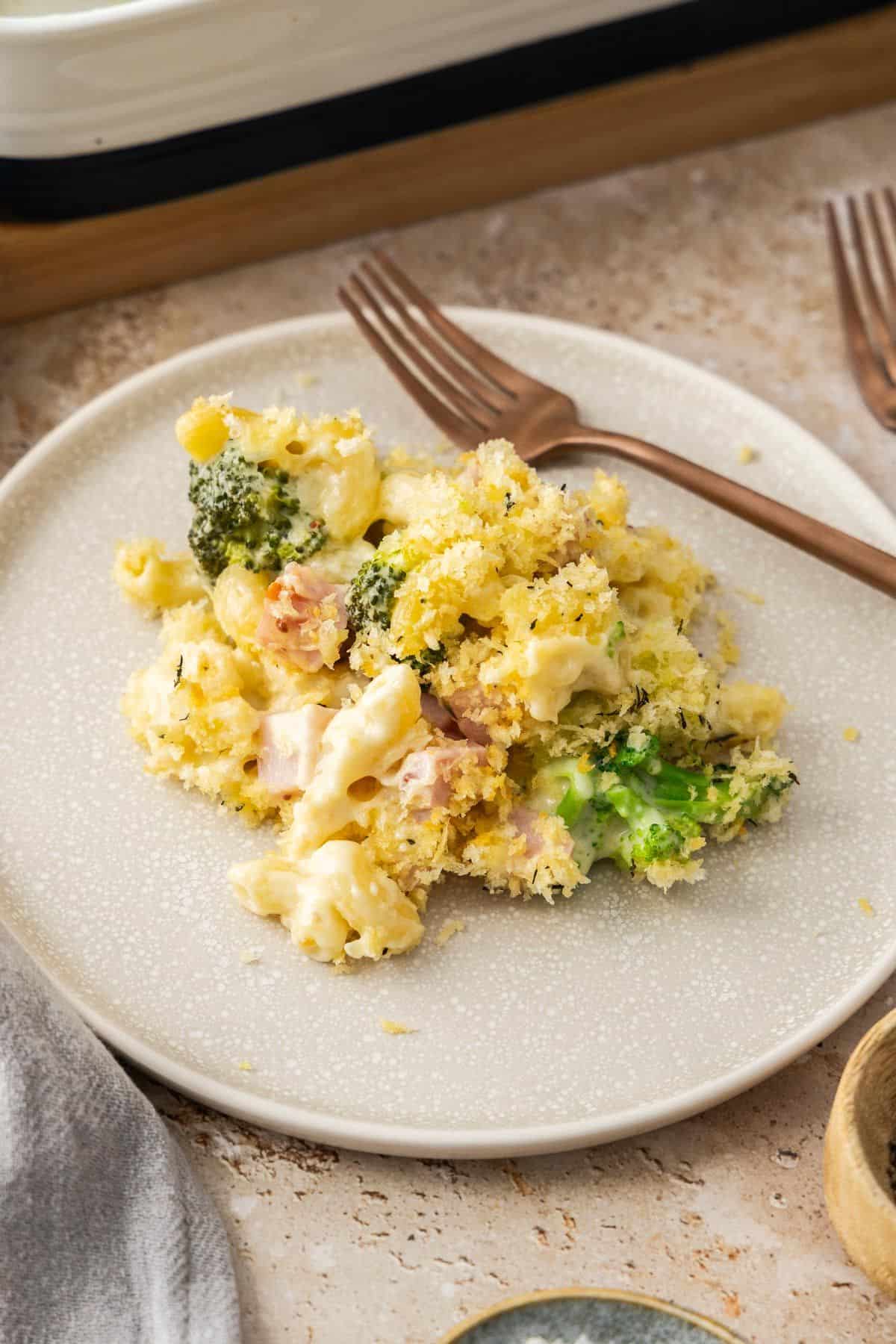 Serving of Creamy Ham Pasta Bake on a round grey plate with a fork on the edge.