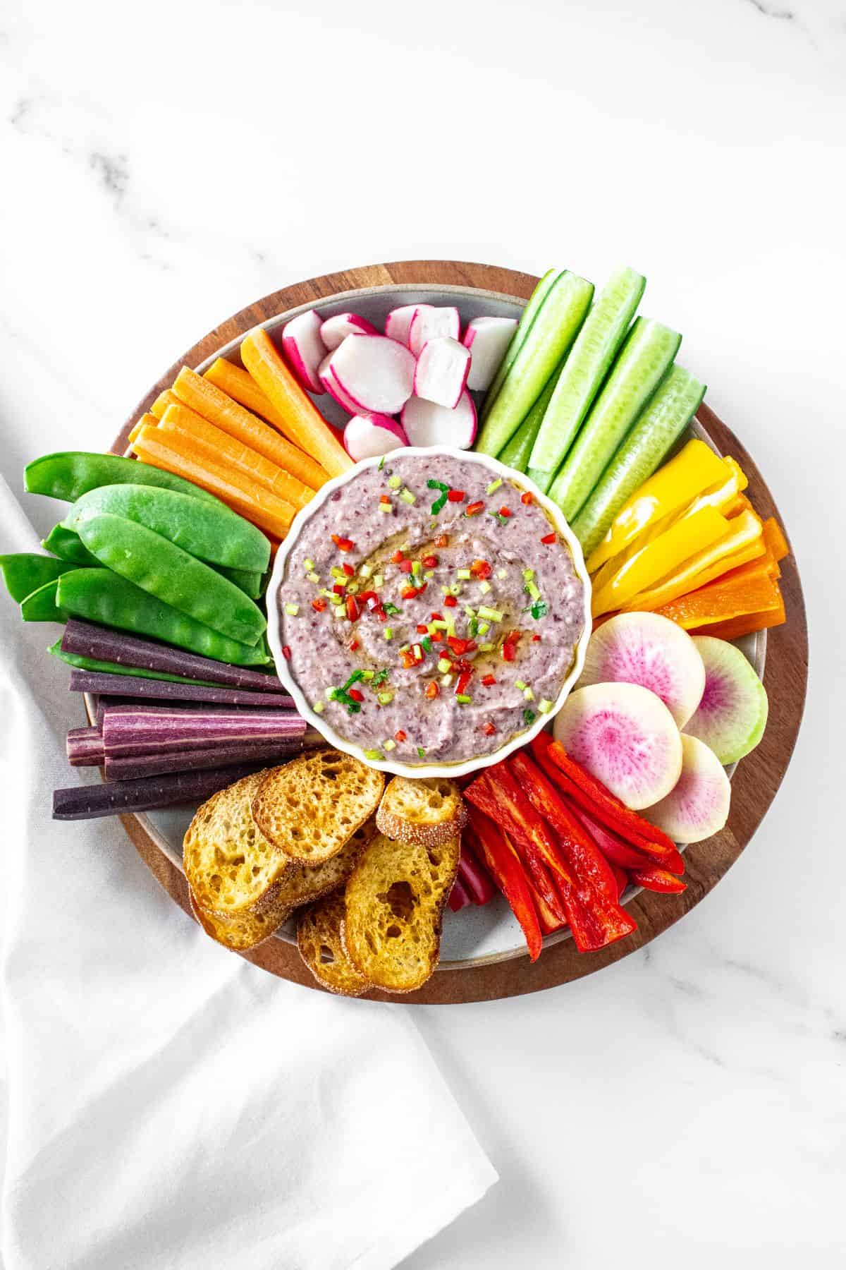 Dip platter featuring Red Kidney Bean Dip and a selection of sliced vegetables and some toasts.